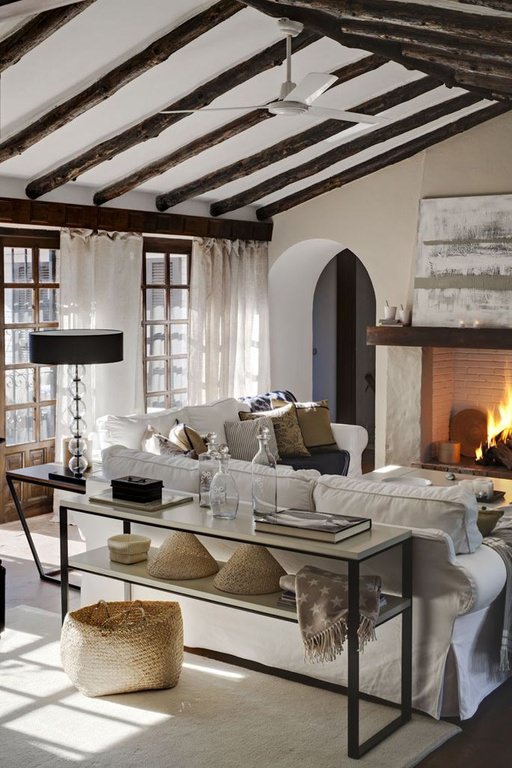 The rugged native look of the living room is made even more attractive by the exposed log beams on the white ceiling.