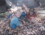 children jumping in leaf pile 