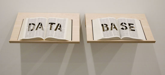 An image of a sculpture with two books on stands with the words data and base carved out of the pages