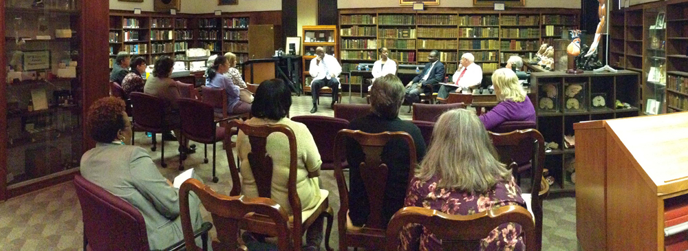 Photograph taken during panel discussion of African American Academic Surgeons held inside the Greenblatt Library's Historical Collections and Archives room. Image taken from the back of the room and shows attendees facing the speakers who are seated. Taken January 22, 2015.