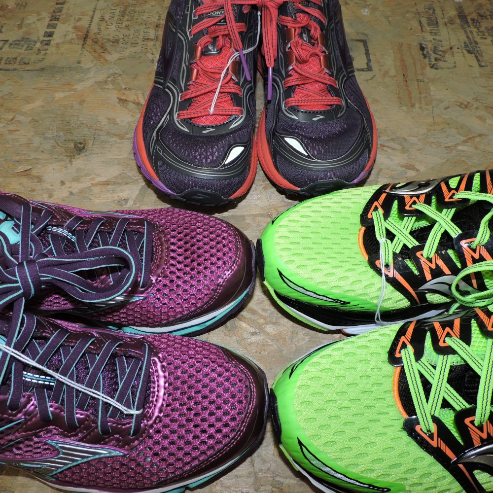 three pairs of tennis shoes, purple on left, green on right, black and red in back center