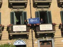 Rosaria & Raphael Harris proudly display the Luxury Real Estate flag at their office in Sicily.