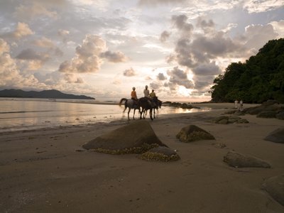 Fine Art Print of Three people sitting on horse in beach at dusk by Assaf Frank