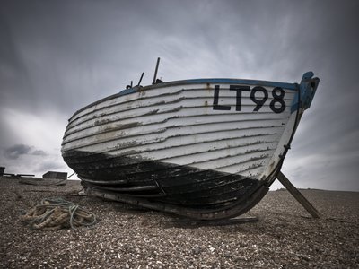 Fine Art Print of Old fishing boat on pebbled beach by Assaf Frank