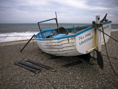 Fine Art Print of Old fishing boat on pebbled beach by Assaf Frank
