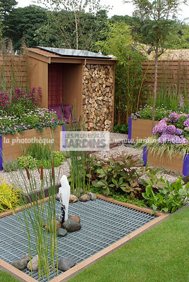 Abri de jardin dans un jardinet urbain. Jardinière en plastique recyclé. Rodgersia, Hydrangea macrophylla 'Teller Blue', Grille en fer. Paysagiste : Tim Fowler, TPFS, Angleterre