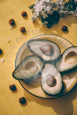Fresh avocado on a yellow background with flowers
