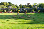 Double domed pergola in oak spans the garden dividing upper gravelled courtyards from the lower lawn featuring maze and central stones. The Collector Earl's Garden designed by Julian and Isabel Bannerman. Arundel Castle Gardens, Arundel, West Sussex, UK