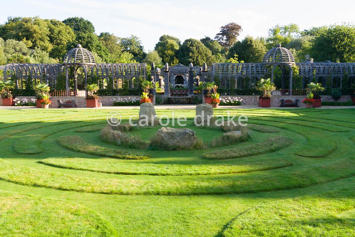 Double domed pergola in oak spans the garden dividing upper gravelled courtyards from the lower lawn featuring maze and central stones. The Collector Earl's Garden designed by Julian and Isabel Bannerman. Arundel Castle Gardens, Arundel, West Sussex, UK