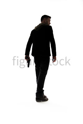 A Figurestock image of a man with a gun, in silhouette, walking away – shot from low level.