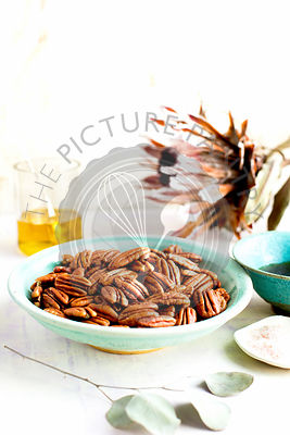 Caramelized Pecans. Photographed on a lavender/white background.