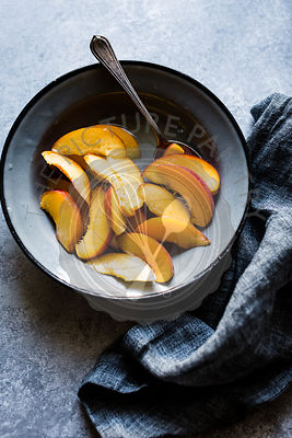 Sliced peaches in a bowl with spoon and napkin