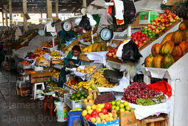 Woman selling fresh fruit on stall in San Pedro market, Cusco, Peru