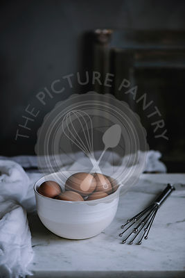 Eggs in a bowl on a marble worktop in a rustic kithcen