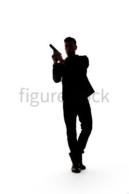 A Figurestock image of a man, in silhouette, walking with a gun – shot from low level.