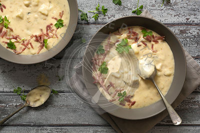 Potato and leek soup garnished with chopped parsley and bacon.