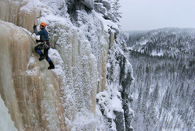 Ice climbing above winter forest landscape
