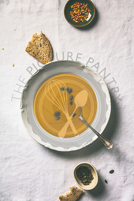 Autumn pumpkin cream soup on white tablecloth