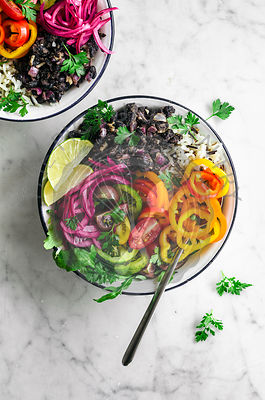 Vegan burrito bowls with spicy black beans, rice, summer vegetables, and pickled onons