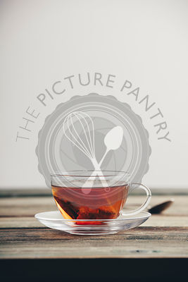 A cup of tea on the wooden table against the white wall