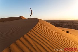 Oman, Wahiba Sands. Tourist jumping on the sand dunes