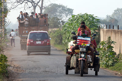 Farmers transporting cauliflower on old three-wheel motorcycles pass in front of the Dhapa Dumping Grounds, the primary landfill for Kolkata, India.