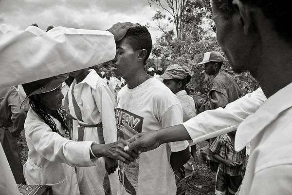 MANGALAZA COMMUNE - "Mpanazary" in the middle of a trans session. They are members of the ANTALAOTRA association, the largest cultural association in this part of Madagascar, whose mission is to promote and make known the rites, cults and traditions of the Alaotra Mangoro region, a sacred region according. Created in 2014, the association already has 37,000 members. Most of them are Mpanazary that can be translated as spiritual guide, diviner, medium. The literal translation is "bewitching". The Mpanazary are almost considered as " demi-gods ". Their dreams, predictions and premonitions are respected and followed by the people of the region and even by the civil and administrative authorities. The region around Lake Alaotra (North-East of Madagascar) is one of the richest agricultural regions in Madagascar. It is considered the "rice granary" of the Big Island. Some argue without hesitation that it is because of the sacred character of the region and its particular cultural practices that the region is so prosperous. Today, as every year, the local population and some Mpanazary go to a sacred hill near the village of Mangalaza to invoke the spirits of the ancestors (Tromba) and ask Zanahary (animist Malagasy God) and Andriamanitra (Christian God) to kindly bring again the beneficial rains for next October that will grow the crops. Each Mpanazary has its specialty: some can bring rain, some can stop cyclones, others can drive out evil spirits. The patients take the opportunity to be treated by the Mpanazary-healer. .