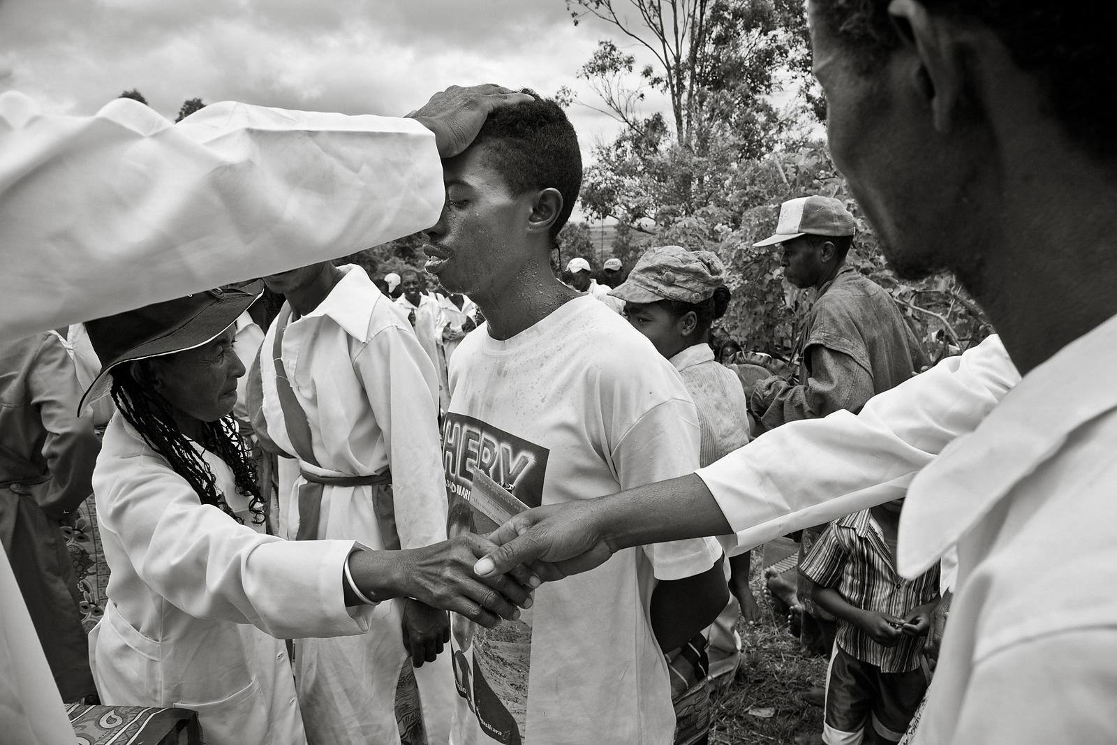 MANGALAZA COMMUNE - "Mpanazary" in the middle of a trans session. They are members of the ANTALAOTRA association, the largest cultural association in this part of Madagascar, whose mission is to promote and make known the rites, cults and traditions of the Alaotra Mangoro region, a sacred region according. Created in 2014, the association already has 37,000 members. Most of them are Mpanazary that can be translated as spiritual guide, diviner, medium. The literal translation is "bewitching". The Mpanazary are almost considered as " demi-gods ". Their dreams, predictions and premonitions are respected and followed by the people of the region and even by the civil and administrative authorities. The region around Lake Alaotra (North-East of Madagascar) is one of the richest agricultural regions in Madagascar. It is considered the "rice granary" of the Big Island. Some argue without hesitation that it is because of the sacred character of the region and its particular cultural practices that the region is so prosperous. Today, as every year, the local population and some Mpanazary go to a sacred hill near the village of Mangalaza to invoke the spirits of the ancestors (Tromba) and ask Zanahary (animist Malagasy God) and Andriamanitra (Christian God) to kindly bring again the beneficial rains for next October that will grow the crops. Each Mpanazary has its specialty: some can bring rain, some can stop cyclones, others can drive out evil spirits. The patients take the opportunity to be treated by the Mpanazary-healer. .