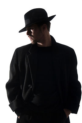 A Figurestock image of a mystery man in a black coat and Fedora hat, in silhouette – shot from eye level.
