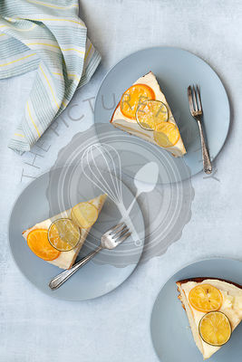 Slices of iced orange cake on plates with forks.