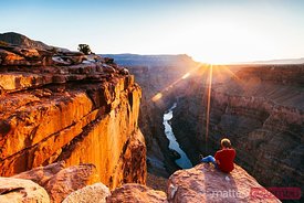 Tourist on the edge of the Grand Canyon at sunrise, USA