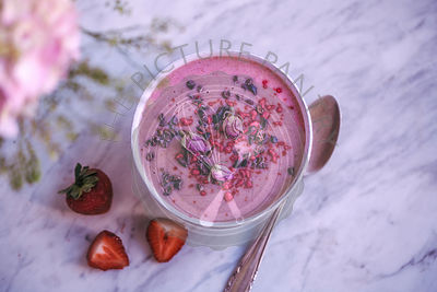 Strawberry smoothie bowl topped with cacao nibs, raspberry powder and rose buds