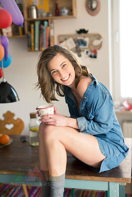 Portrait of laughing woman sitting on kitchen table with coffee mug