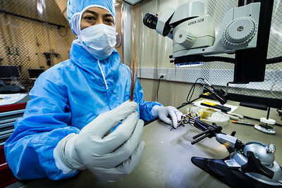 Ingénieur met en place le câblage d'éléments du sismomètre ultrasensible SEIS Seismic Experiment for Interior Structures, dans une hotte à flux laminaire d'une salle blanche de l'entreprise Sodern.
