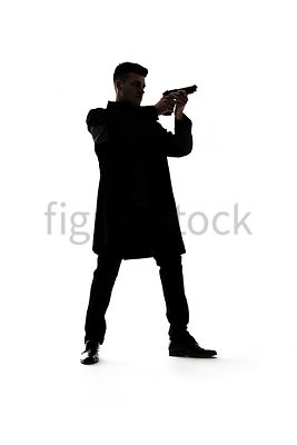A Figurestock image of a mystery man standing, painting a gun, in silhouette – shot from low level.