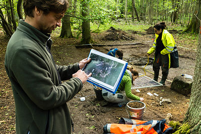 Olivier Weller avec une photo du film près de la zone de fouille de la cabane.