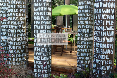 Coin repas au potager. Table, chaise, parasol. Décoration insolite : colonne. Designer : Paul Stone. Chelsea FS, Angleterre