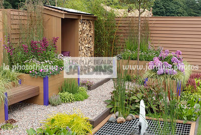 Abri de jardin dans un jardinet urbain. Jardinière en plastique recyclé. Carex elata 'Aurea', Geranium sanguineum, Hydrangea macrophylla 'Teller Blue', Grille en fer. Paysagiste : Tim Fowler, TPFS, Angleterre