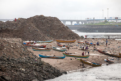 Fishing boats amid piles of garbage on the shore of Mahim Bay (Arabian Sea), Mahim, Mumbia, India.