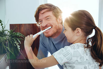 Daughter brushing her father’s teeth in bathroom
