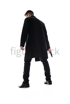 A Figurestock image of a mystery man standing, holding a gun – shot from low level.