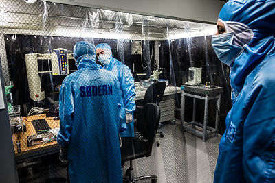 Ingénieurs préparent le montage des éléments du sismomètre ultrasensible SEIS Seismic Experiment for Interior Structures, devant une hotte à flux laminaire d'une salle blanche de l'entreprise Sodern.