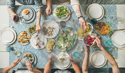 Flat-lay of hands holding mediterranean starters and various drinks