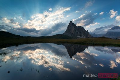 Mountain peak and clouds reflected in alpine lake in the Dolomites