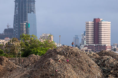 Children play barefoot on a mound of garbage in Mahim Bay, Mumbai, India.