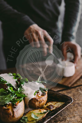 Man's hand cutting cheese on wooden board. Preparation for lunch. Rustic backgraund