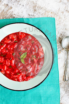 Strawberry Basil Jam served in a enamel bowl. Photographed on a rustic white background.