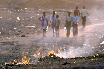 Women sweep up and burn garbage on a dusty desert road after the Pushkar Camel Fair, Pushkar, Rajasthan, India. Air pollution is an epidemic health crisis across India. India has the worst air pollution in the world, worse even than China, with Delhi the #1 worst city in the world.