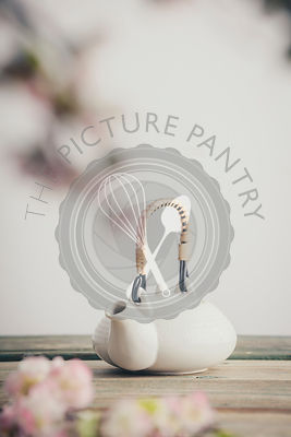 White teapot and sakura flowers on wooden table against the white wall