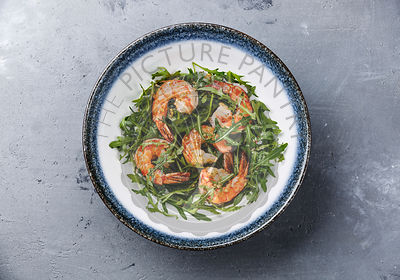Arugula salad with prawn shrimp on gray concrete background